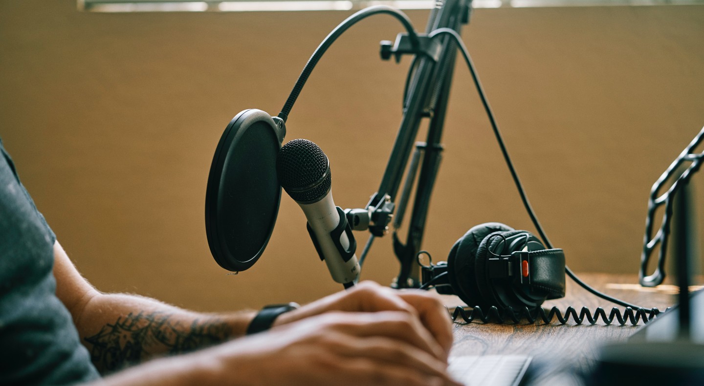 A close up of a white man's hands near some podcasting equipment.